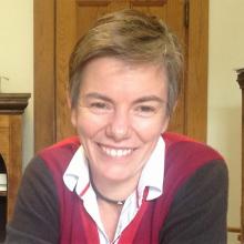 Headshot of woman with short hair, wearing collared color-blocked shirt, smiling at the camera