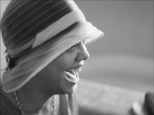 Head shot of black woman wearing a bonnet, looking sideways and laughing 