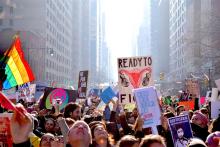 Line of protestors with various signs including one reading "Ready to Fight" which features fallopian tubes wearing boxing gloves