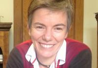 Headshot of woman with short hair, wearing collared color-blocked shirt, smiling at the camera