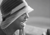 Head shot of black woman wearing a bonnet, looking sideways and laughing 