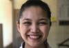 Upper body shot of Marielle Marcaida with her hair slicked back into a ponytail, wearing a white collared shirt, and smiling at the camera.