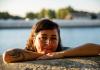 Dr. Burneo Salazar with her chin propped up on her crossed arms which are resting on a cement wall. She's in a body of water.