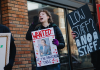 Daisy Federspiel-Baier holding a protest sign and chanting outside a Starbucks store.