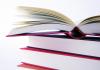 Stack of three red books. The top book is open. White background. 