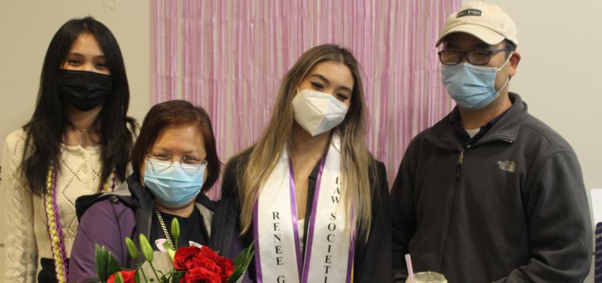 A group of four people standing under a congrats banner